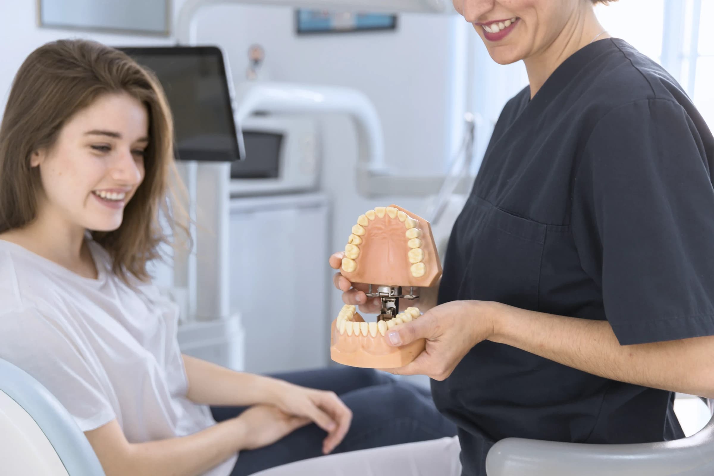 Lékařka ukazuje model chrupu s ortodontickým aparátem
